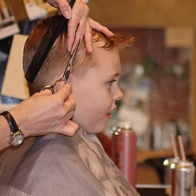 a kid getting a haircut in a salon