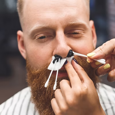 a man getting his nose waxed in a barbershop